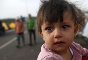 A girl cries at the "Horgos 2" border crossing into Hungary, near Horgos, Serbia, Thursday, Sept. 17, 2015. Thousands of migrants poured into Croatia on Thursday, setting up a new path toward Western Europe after Hungary used tear gas and water cannons to keep them out of its territory. (AP Photo/Darko Vojinovic)