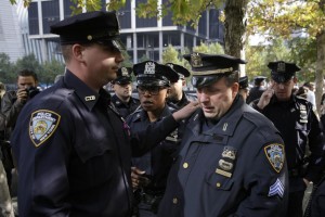 A police officer cries after laying flowers in memory of Officer Randolph Holder at the 9/11 Memorial in New York, Thursday, Oct. 22, 2015.  Tyrone Howard is charged with first-degree murder and robbery, accused of stealing a bike and fatally shooting Holder in the head after a chase Tuesday night.  (AP Photo/Seth Wenig)