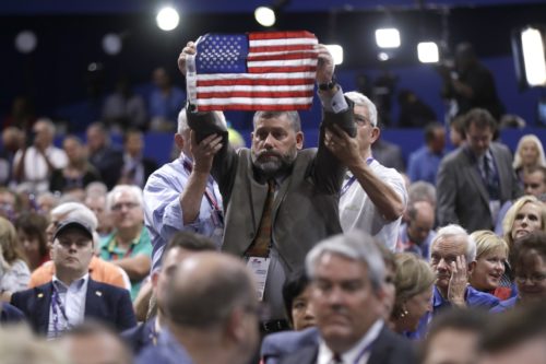 Two delegates support Oregon delegate and Oregon delegate and Afghanistan war veteran Joseph Rice holding up an American flag during first day of the Republican National Convention in Cleveland, Monday, July 18, 2016. (AP Photo/Matt Rourke)